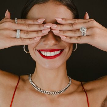 Woman covering her eyes, smiling, wearing jewelry